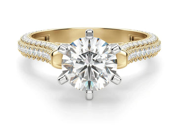 A round-cut moissanite engagement ring with a gold band and pavé set accent stones along the top and arched side.