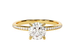Load image into Gallery viewer, A round cut moissanite engagement ring with channel set sidestones, featuring a gold band and a central moissanite stone, surrounded by smaller moissanite stones set in channel settings.