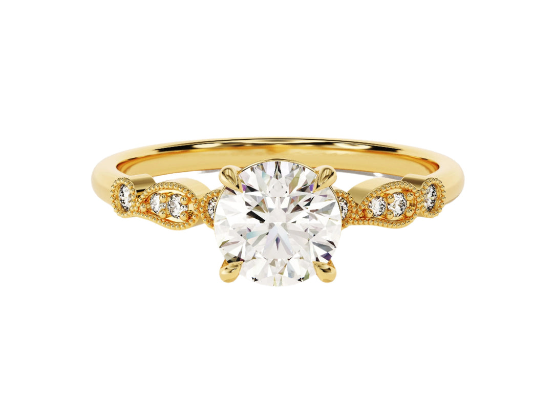A round cut moissanite engagement ring with wave sidestones, set in a gold band with milgrain detailing.