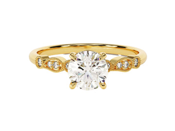 A round cut moissanite engagement ring with wave sidestones, set in a gold band with milgrain detailing.