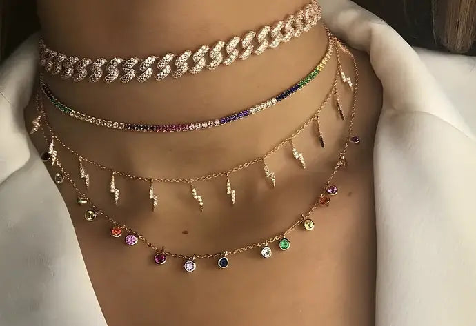 Multiple necklaces with various designs and gemstones on a plain background