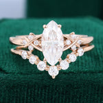 Load image into Gallery viewer, A 1CT Marquise Cut Moissanite Criss Cross Diamond Accented Bridal Ring Set on a green background