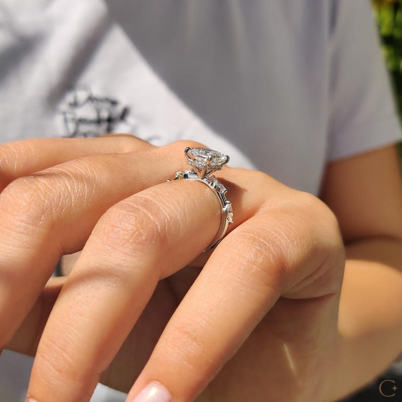 Hidden halo engagement ring includes marquise side stones.