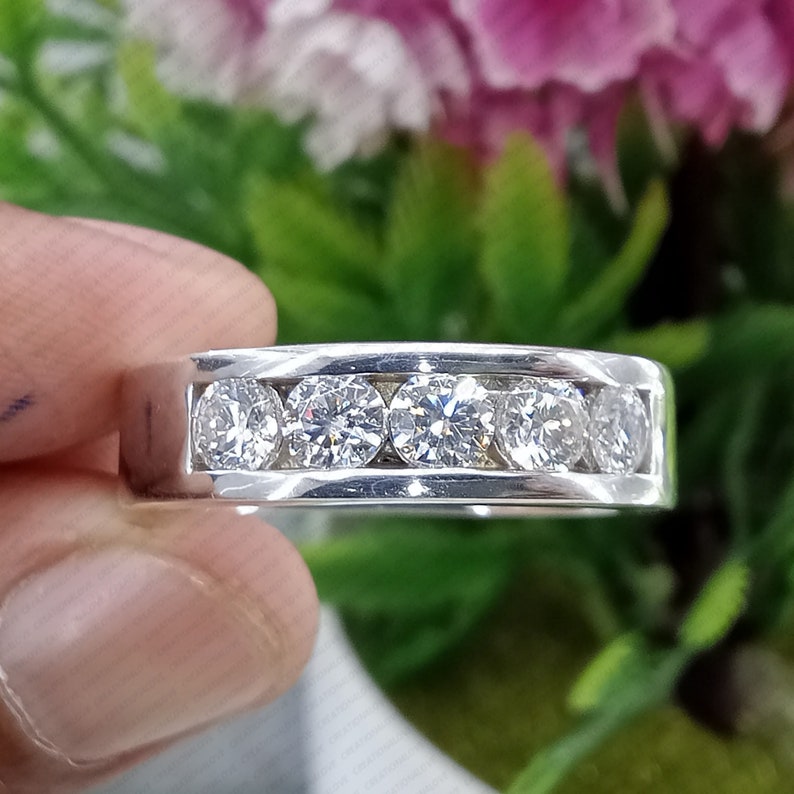 May include: A silver band with six round, clear diamonds set in a channel setting.